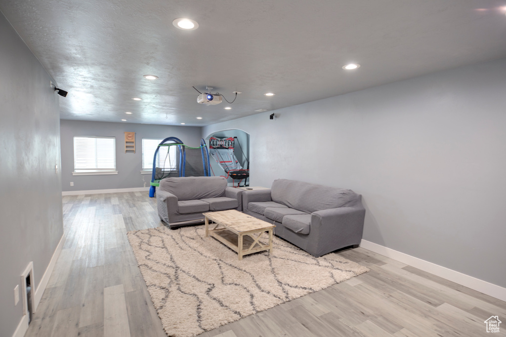 Living room with light wood finished floors, recessed lighting, baseboards, and arched walkways