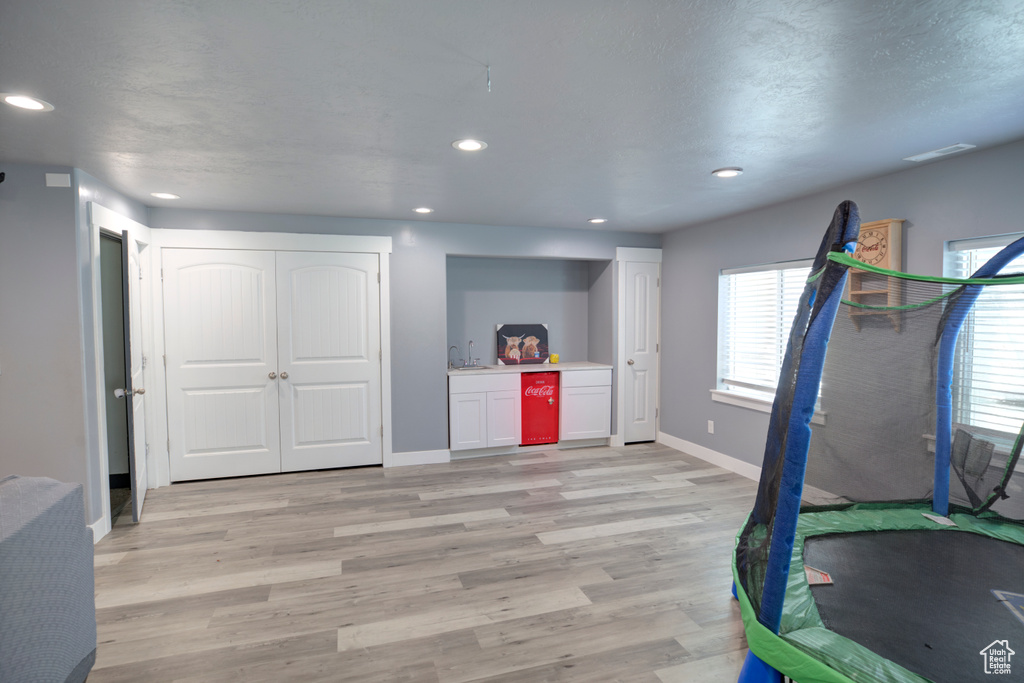 Rec room with light wood-style floors, bar area, recessed lighting, and baseboards