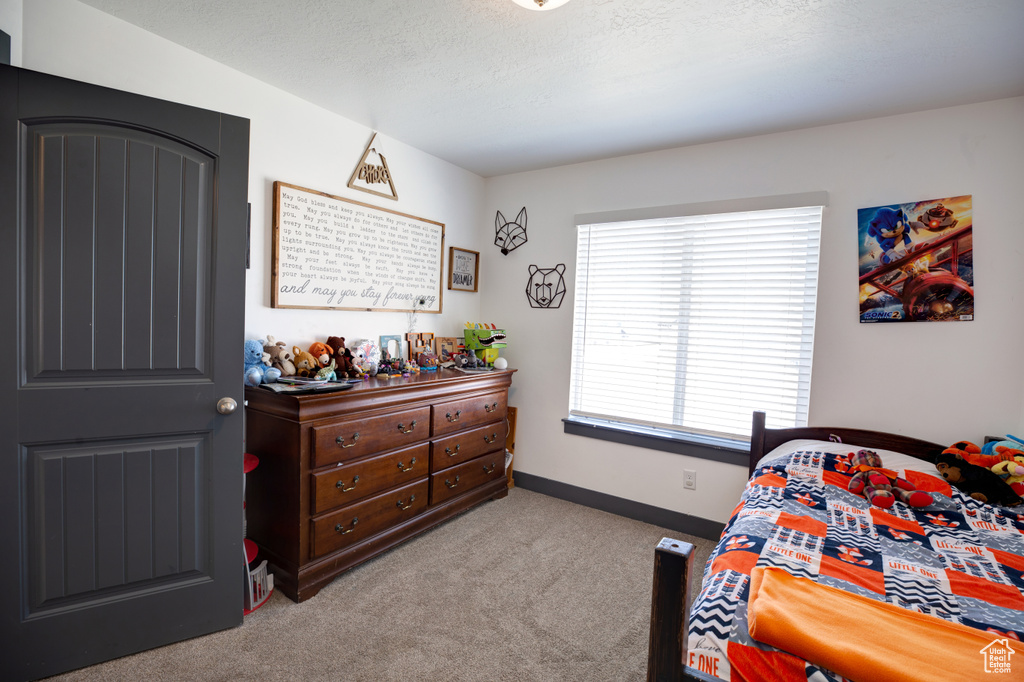 Bedroom featuring carpet, baseboards, and a textured ceiling