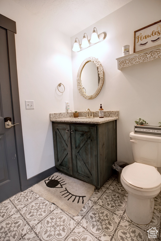 Half bathroom featuring vanity, toilet, and tile patterned flooring