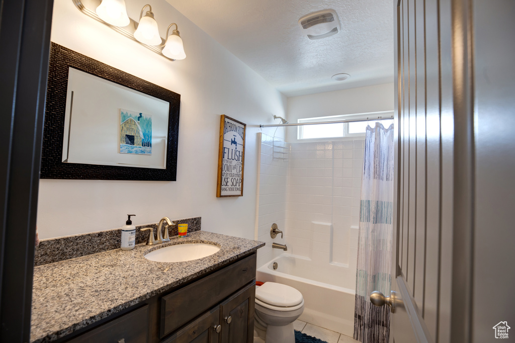 Full bath with toilet, vanity, shower / tub combo with curtain, a textured ceiling, and tile patterned flooring