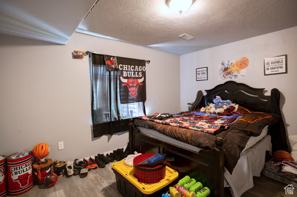 Bedroom featuring wood finished floors and a textured ceiling