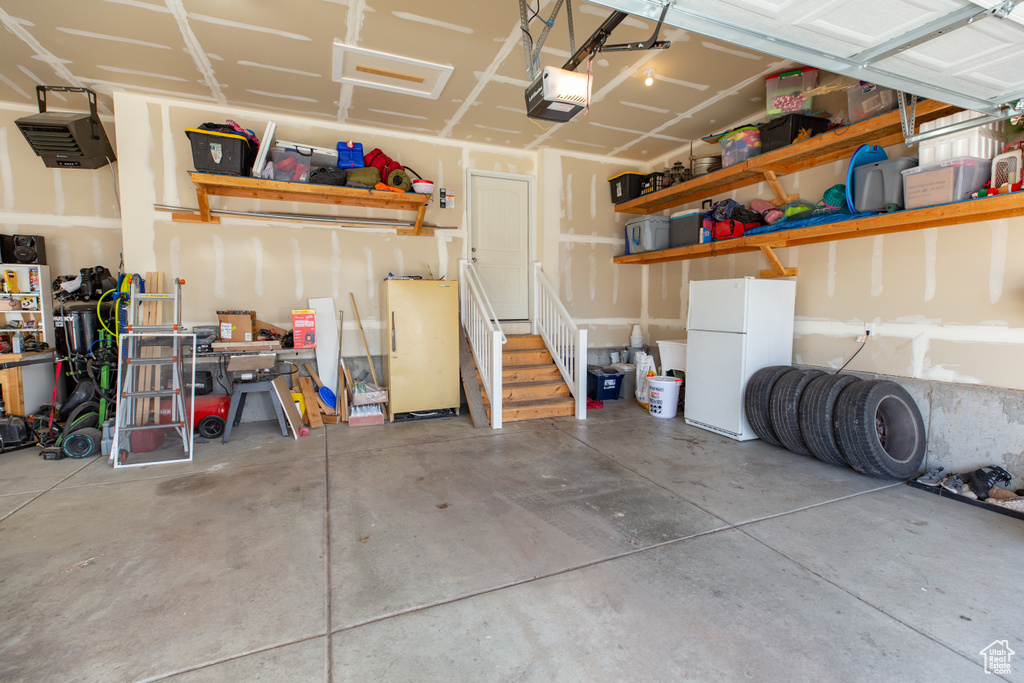 Garage with freestanding refrigerator and a garage door opener