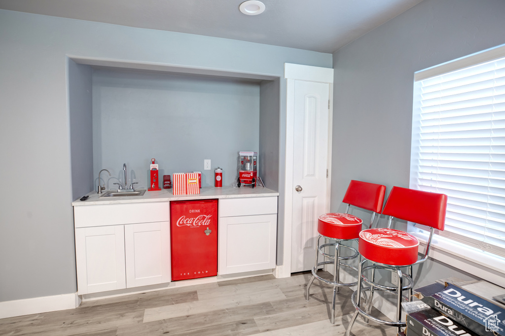Indoor wet bar with light wood-style floors and baseboards