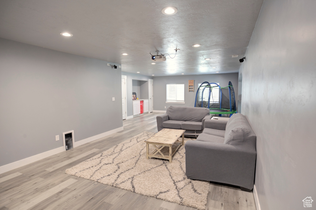 Living room with light wood finished floors, recessed lighting, and baseboards