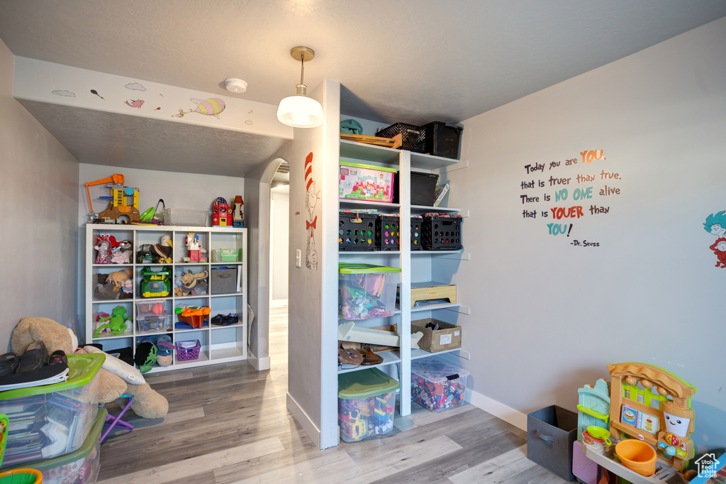 Rec room with wood finished floors, arched walkways, and baseboards