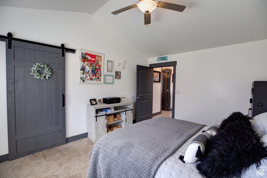 Bedroom with lofted ceiling, light colored carpet, a barn door, ceiling fan, and baseboards
