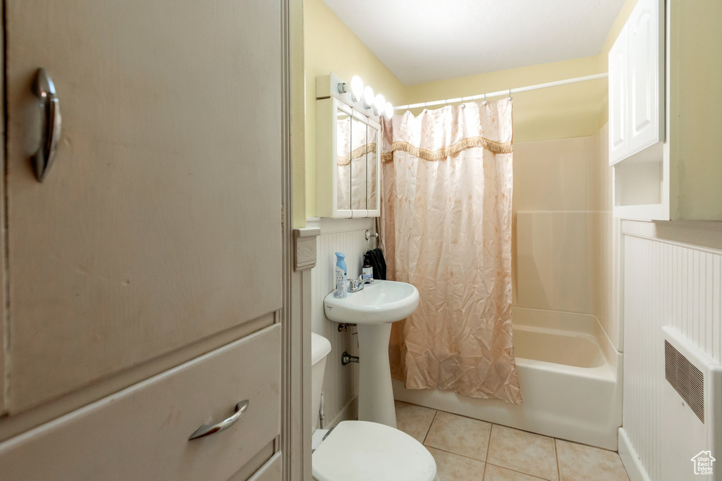 Bathroom with tile patterned flooring, toilet, shower / bath combo with shower curtain, and a sink