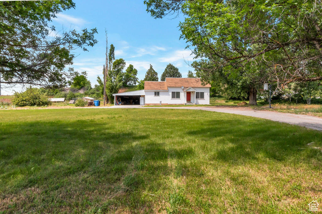 View of front of house with a front lawn, driveway, and a carport