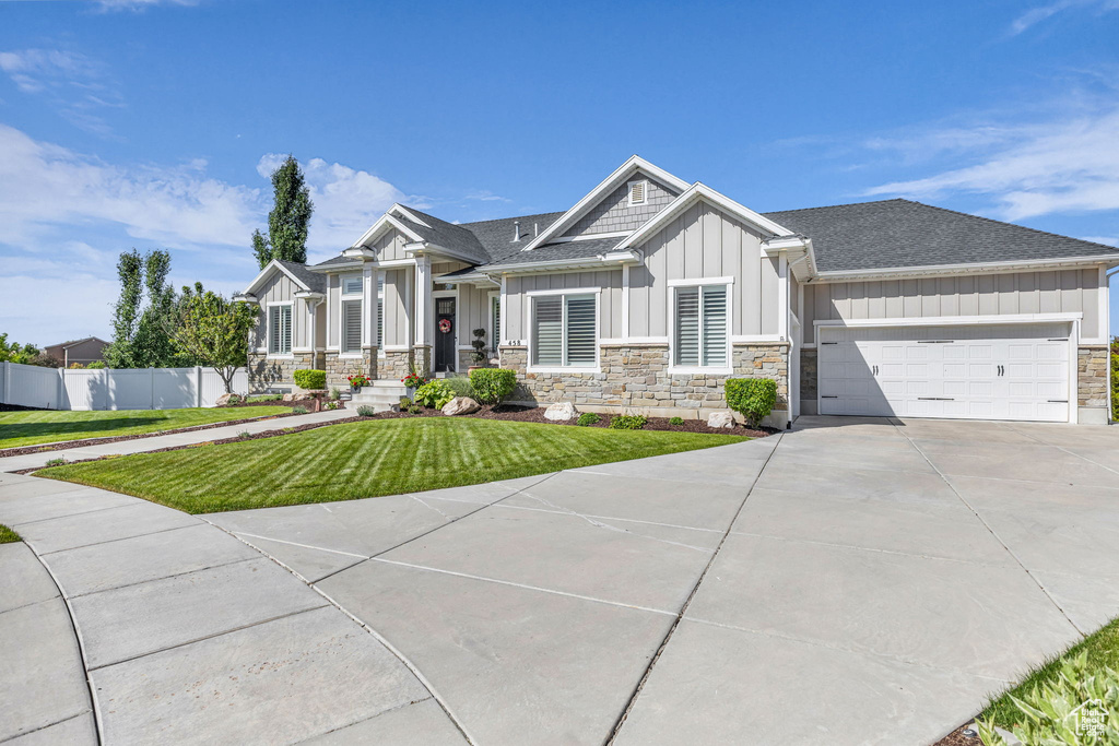 Craftsman-style house featuring board and batten siding, stone siding, an attached garage, concrete driveway, and a shingled roof