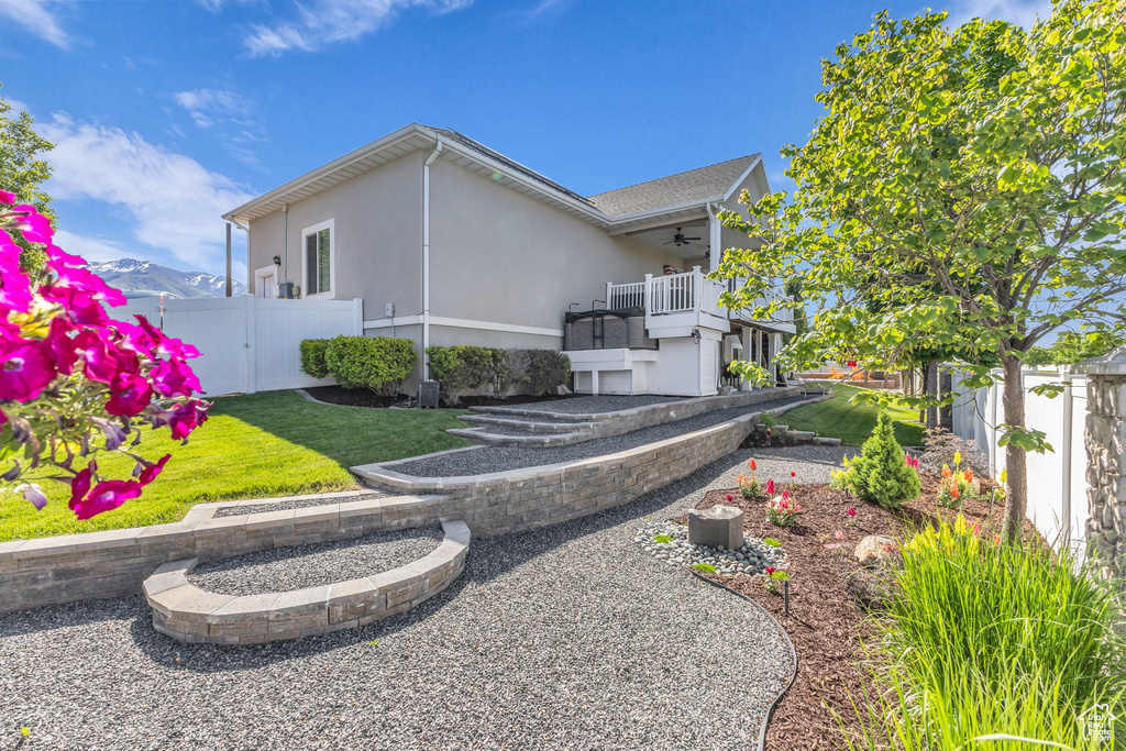 Rear view of property featuring ceiling fan, stucco siding, and a balcony