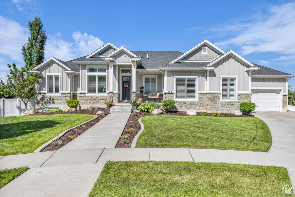Craftsman-style house featuring board and batten siding, stone siding, an attached garage, and roof with shingles