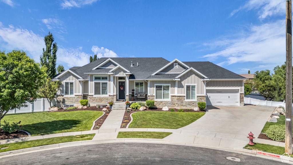Craftsman-style house featuring board and batten siding, stone siding, concrete driveway, roof with shingles, and an attached garage