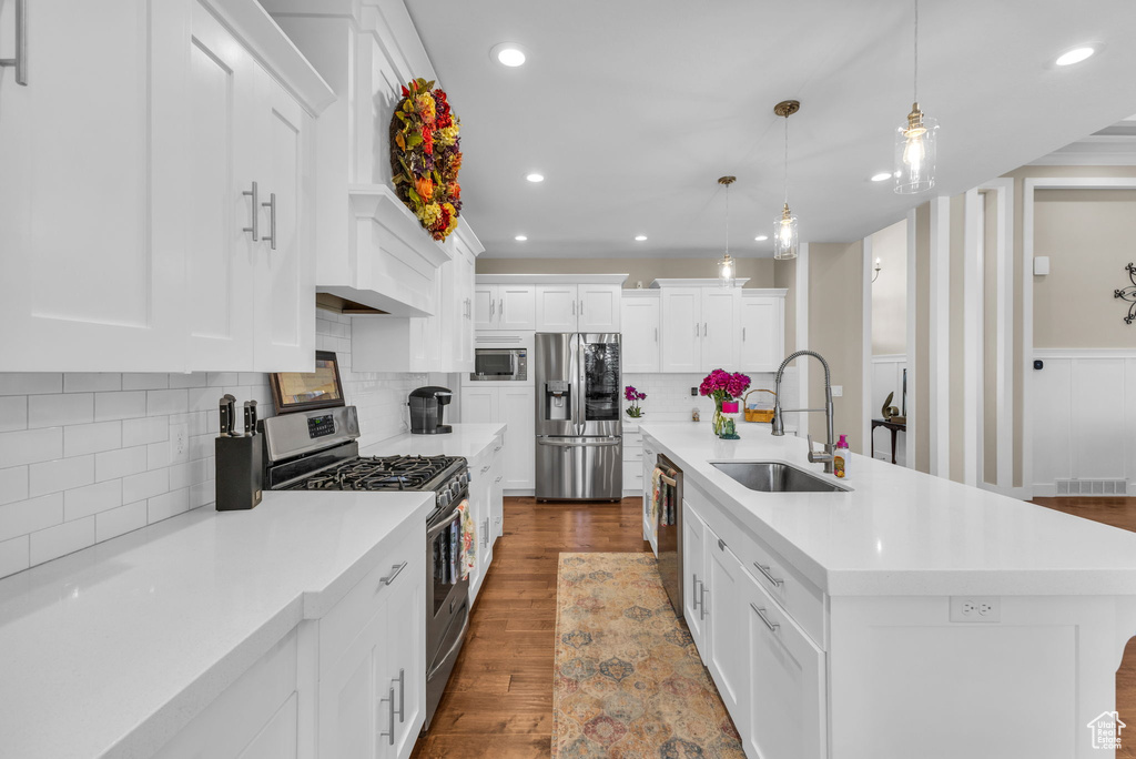 Kitchen with appliances with stainless steel finishes, a sink, white cabinets, light countertops, and recessed lighting