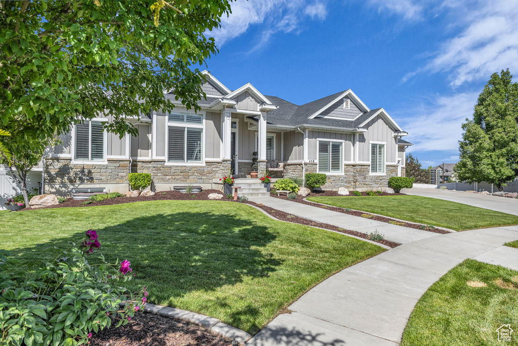 Craftsman-style home featuring board and batten siding, stone siding, and a front lawn