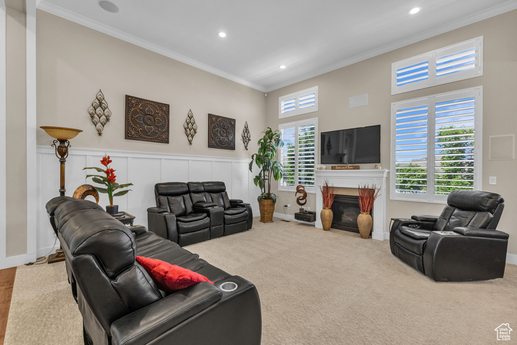 Carpeted living room with crown molding, recessed lighting, a glass covered fireplace, and wainscoting