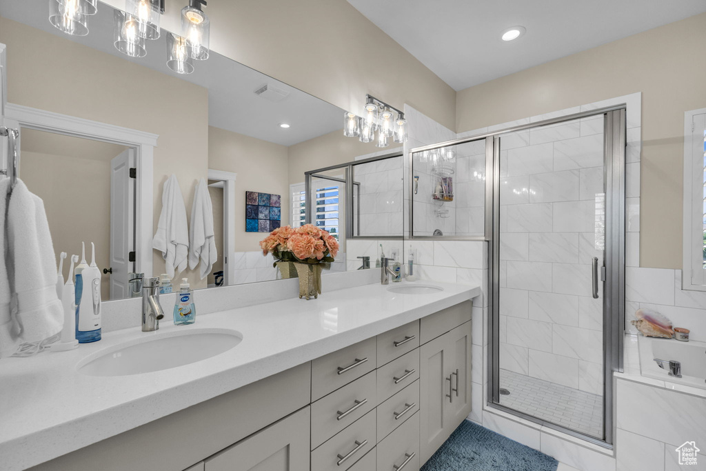 Full bathroom with double vanity, a shower stall, and recessed lighting