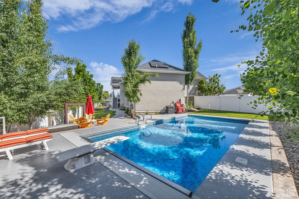 View of swimming pool with a patio area, a fenced backyard, and a diving board