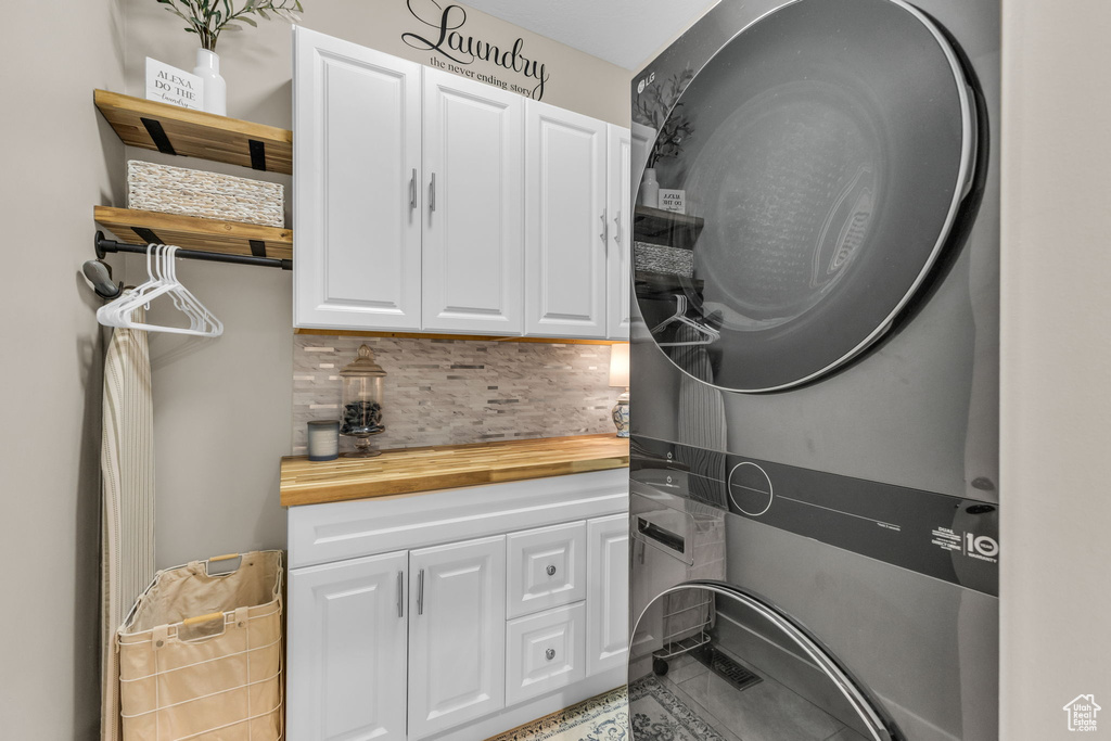Washroom with cabinet space, stacked washer and clothes dryer, and tile patterned floors