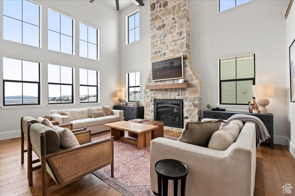 Living area with a stone fireplace, a high ceiling, baseboards, and hardwood / wood-style flooring