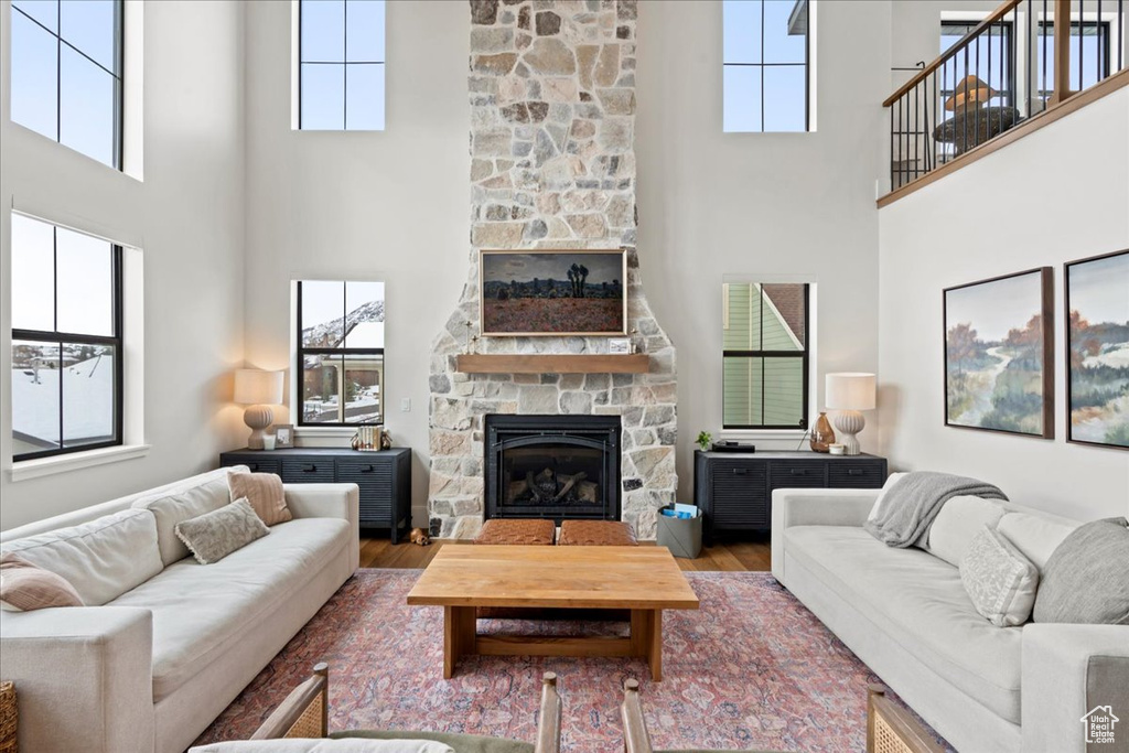Living area featuring a fireplace, a high ceiling, wood finished floors, and healthy amount of natural light