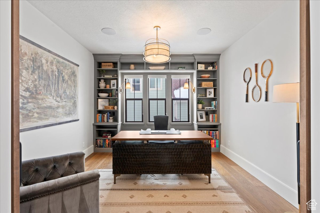 Office area featuring baseboards, light wood-style floors, and built in features
