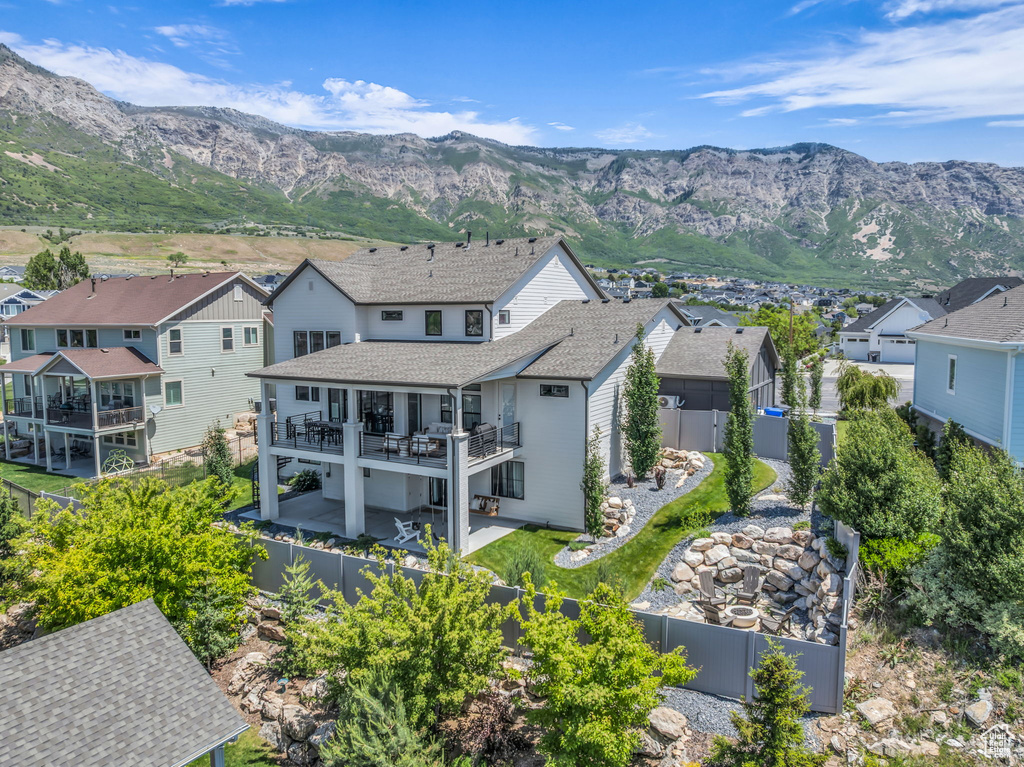 Back of house with a fenced backyard, a residential view, a patio, a deck with mountain view, and a shingled roof