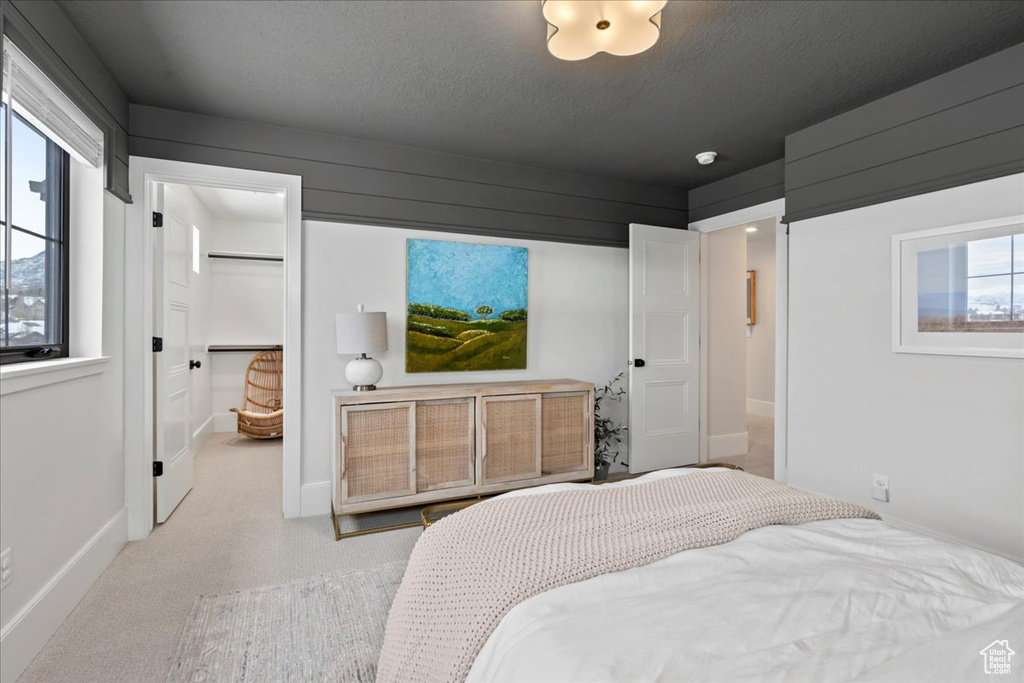 Bedroom with a walk in closet, baseboards, a textured ceiling, and a closet