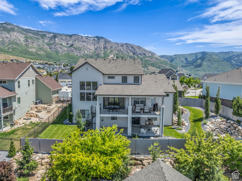 Rear view of house with a residential view, a fenced backyard, roof with shingles, a mountain view, and a gate