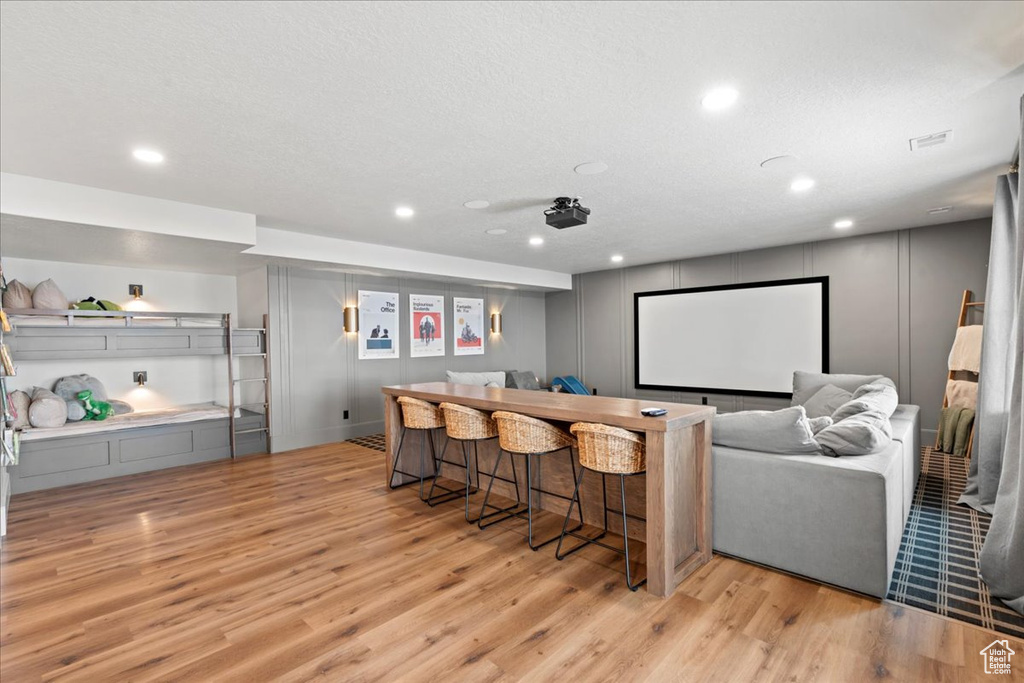 Cinema featuring light wood-style flooring, a dry bar, recessed lighting, and a decorative wall