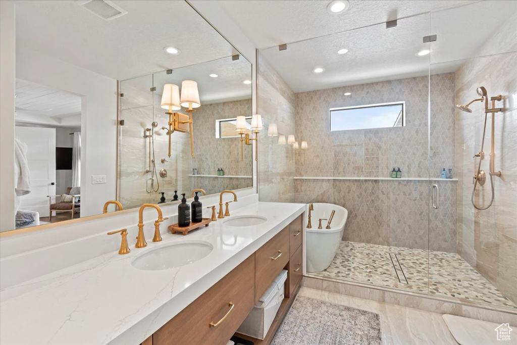Bathroom featuring a stall shower, double vanity, a soaking tub, ensuite bath, and recessed lighting