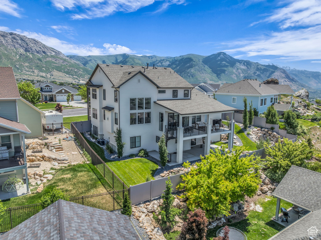 Rear view of property featuring a residential view, a fenced backyard, a deck with mountain view, and a shingled roof