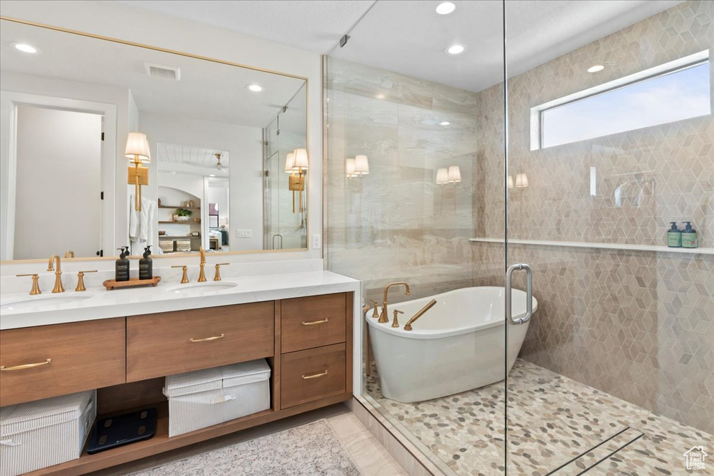 Full bathroom featuring double vanity, a freestanding tub, a shower stall, recessed lighting, and tile patterned flooring