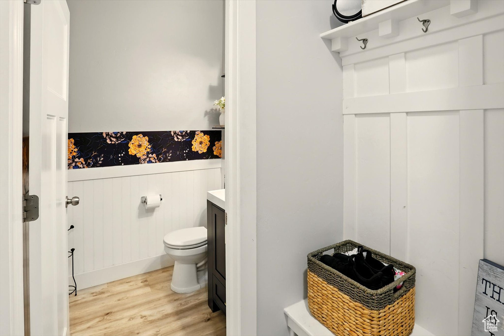 Bathroom with wood finished floors, wainscoting, toilet, and vanity