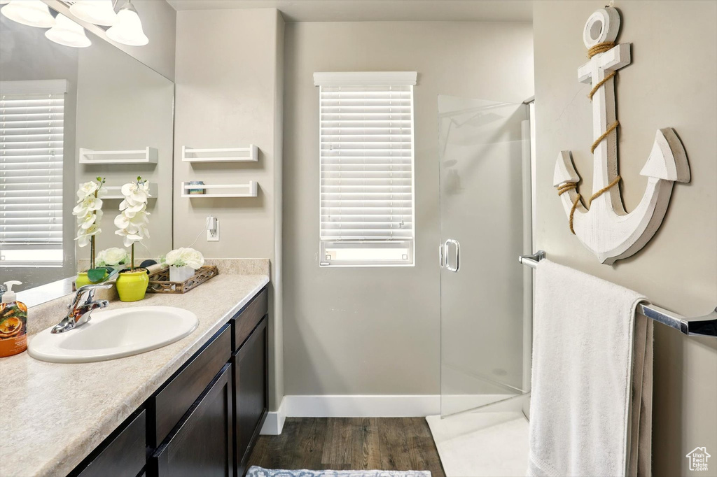 Bathroom featuring a stall shower, vanity, wood finished floors, and plenty of natural light