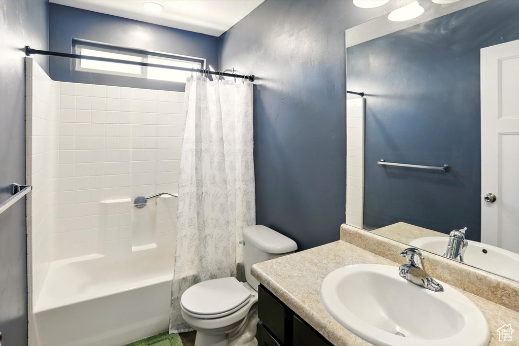 Full bathroom with shower / tub combo with curtain, toilet, and vanity