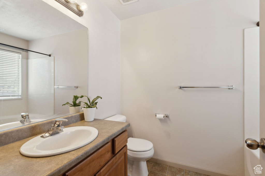 Full bathroom with toilet, vanity, tile patterned flooring, a shower, and baseboards