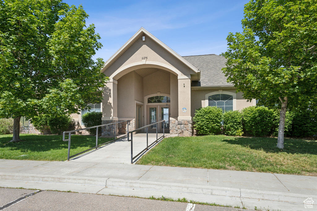 View of front facade featuring stucco siding, french doors, stone siding, a gate, and roof with shingles