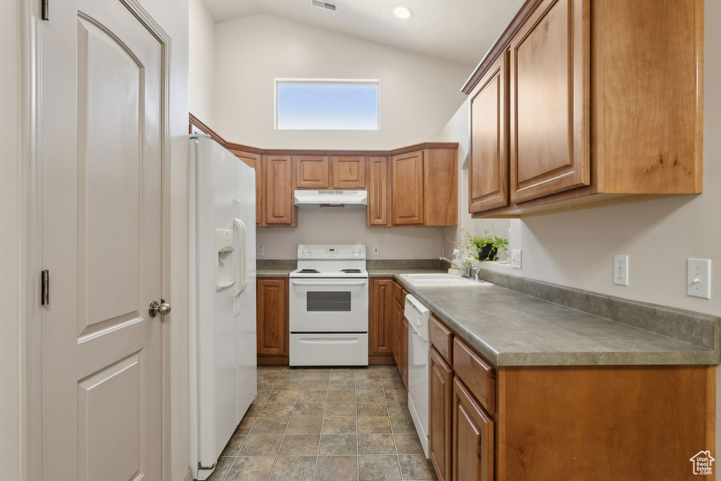 Kitchen with under cabinet range hood, white appliances, a sink, brown cabinets, and high vaulted ceiling