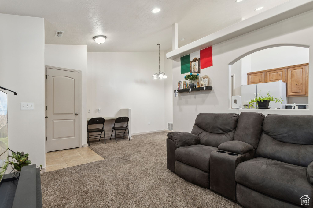 Living area with light colored carpet, a chandelier, light tile patterned floors, arched walkways, and recessed lighting