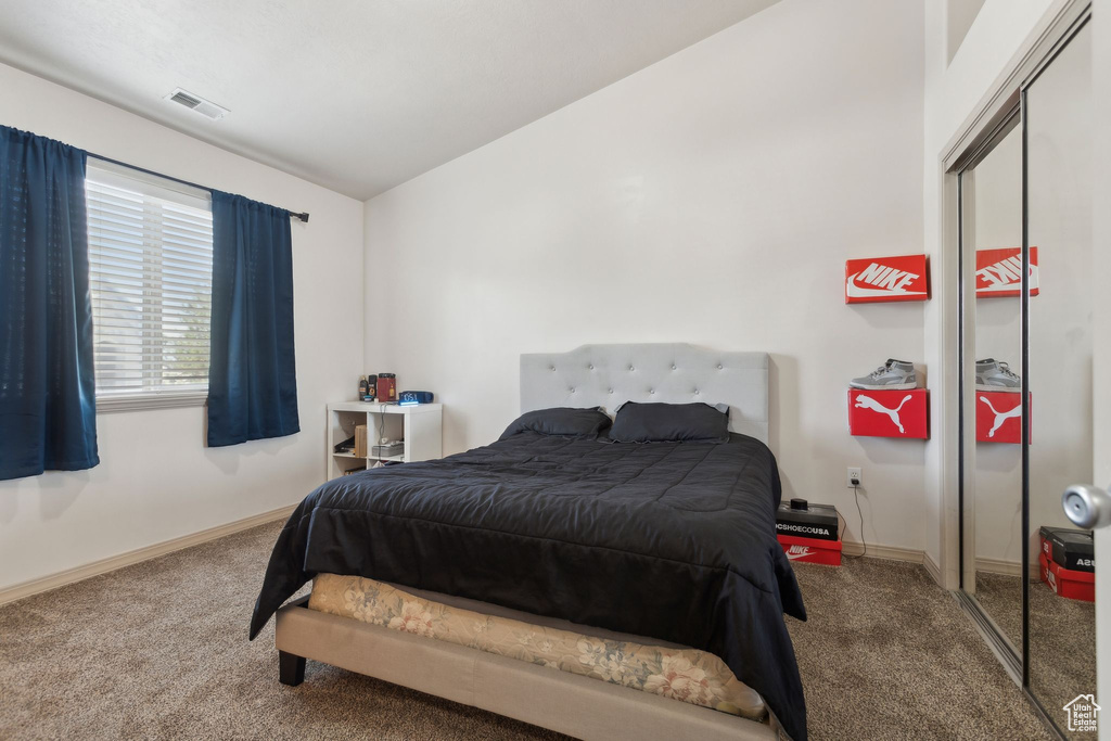 Carpeted bedroom featuring lofted ceiling, baseboards, and a closet