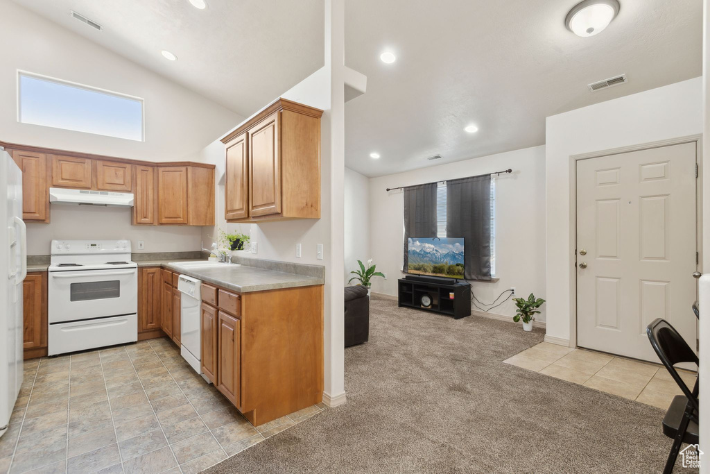 Kitchen with white appliances, under cabinet range hood, light countertops, light carpet, and recessed lighting