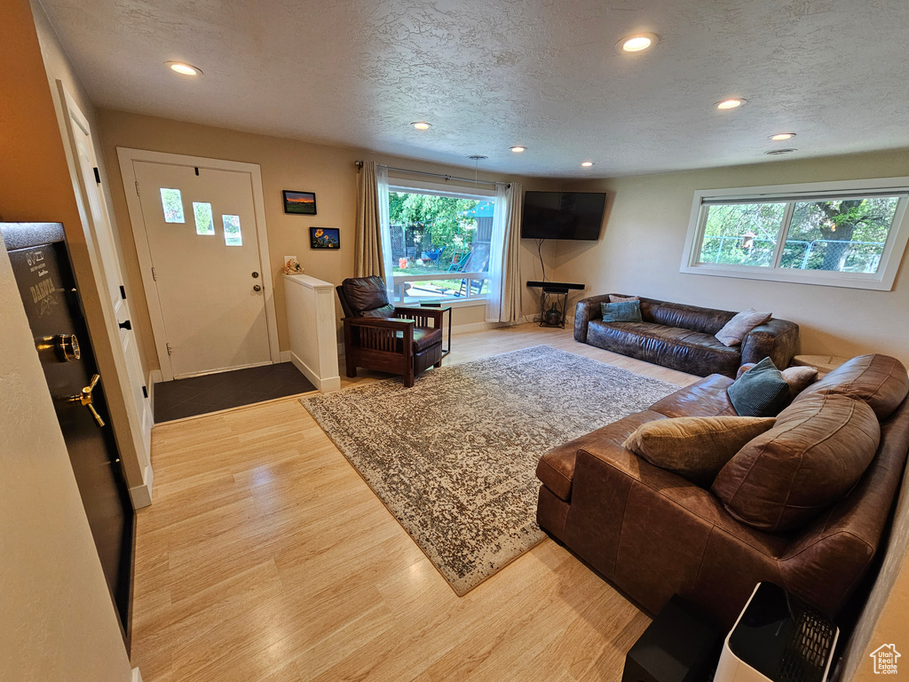 Living room with healthy amount of natural light, wood finished floors, recessed lighting, a textured ceiling, and baseboards