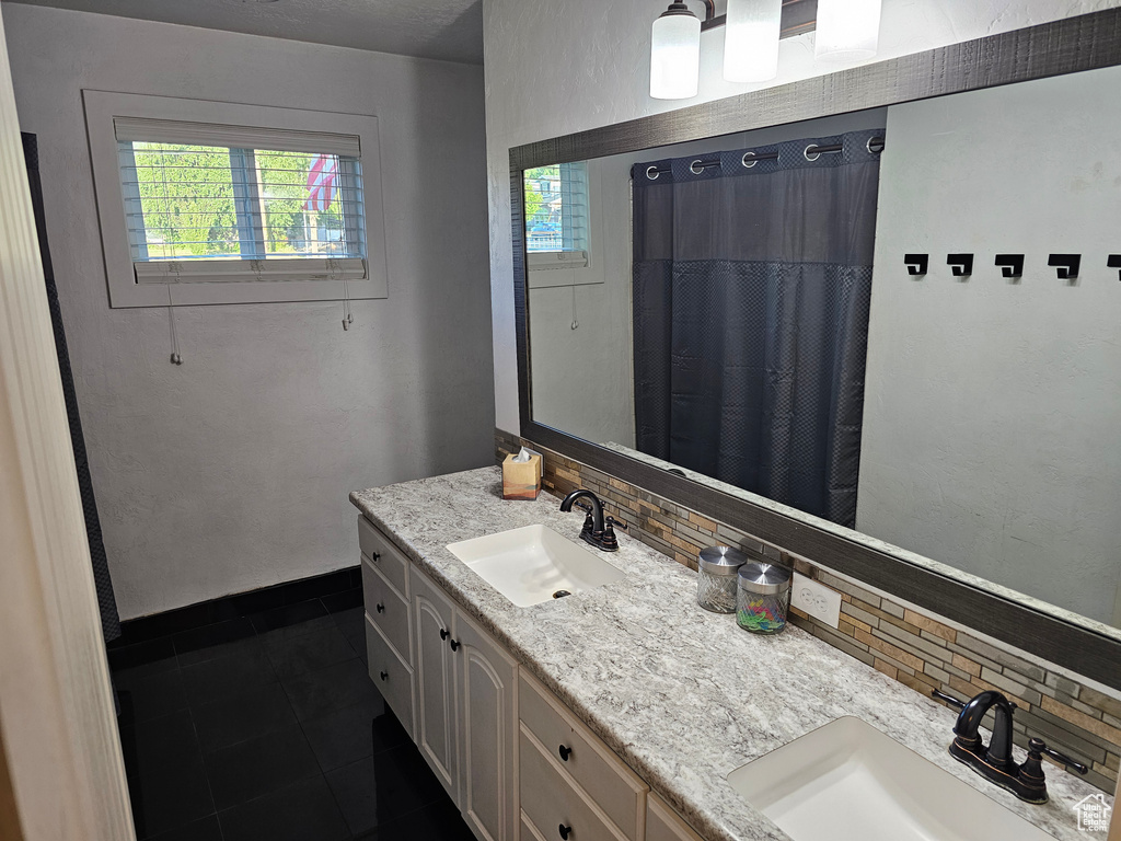 Full bath featuring backsplash, double vanity, tile patterned flooring, and plenty of natural light
