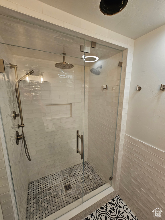 Bathroom featuring a shower stall, wainscoting, and tile walls