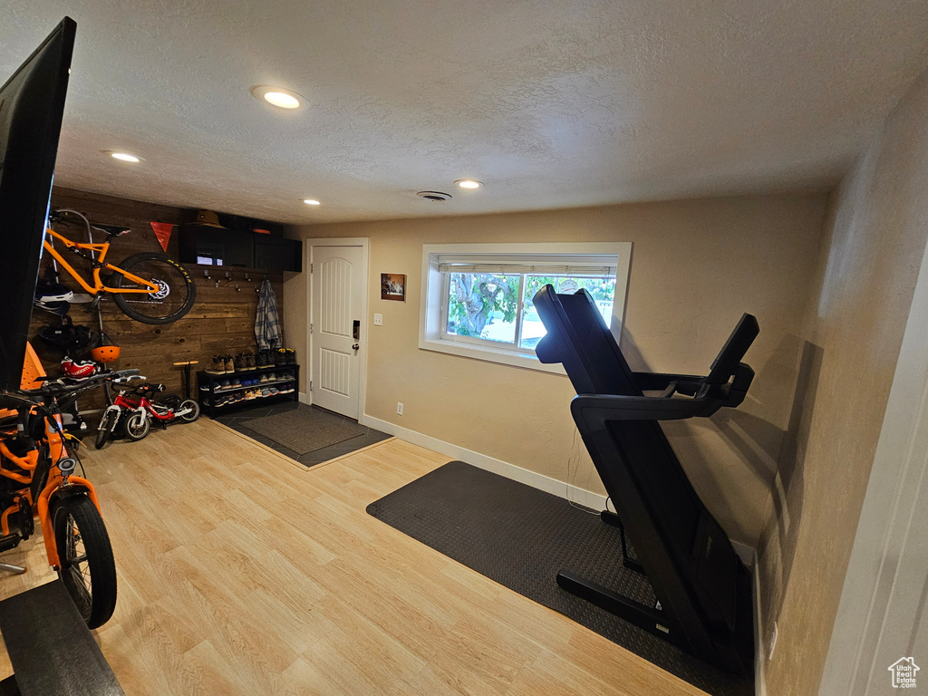 Exercise room with wood finished floors, recessed lighting, a textured ceiling, and baseboards