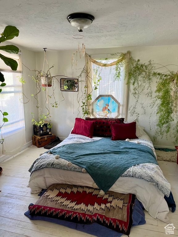 Bedroom featuring multiple windows, wood-type flooring, and a textured ceiling