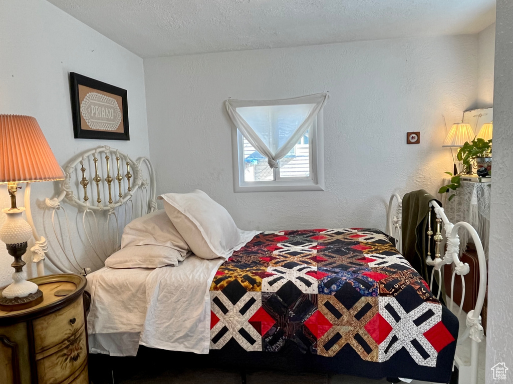 Bedroom with a textured ceiling and a textured wall