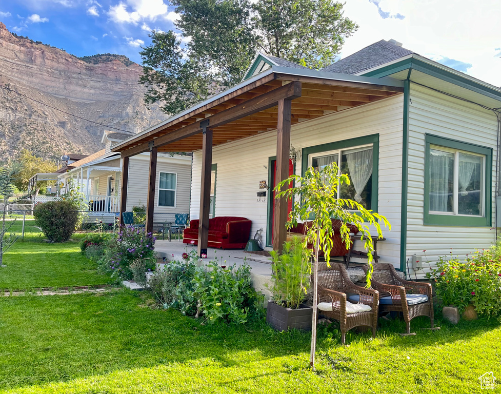 View of property exterior featuring a lawn, covered porch, and a mountain view