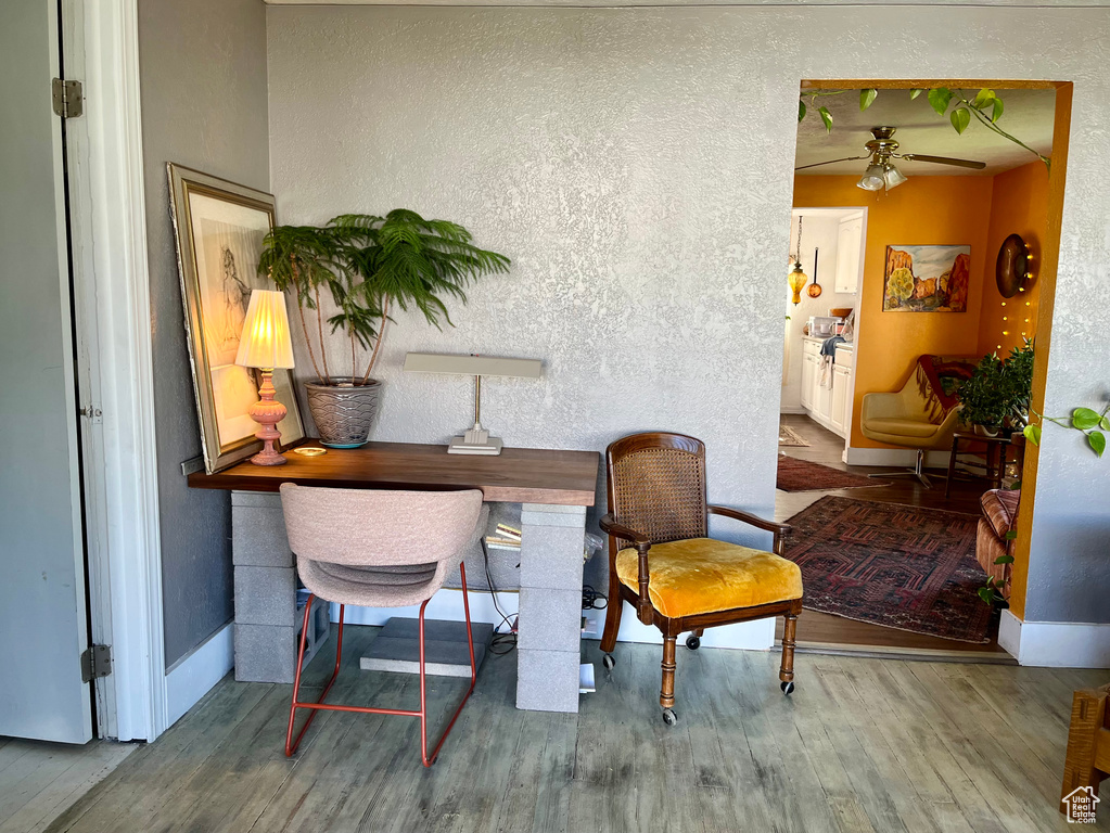 Office space featuring ceiling fan, wood finished floors, a textured wall, and baseboards